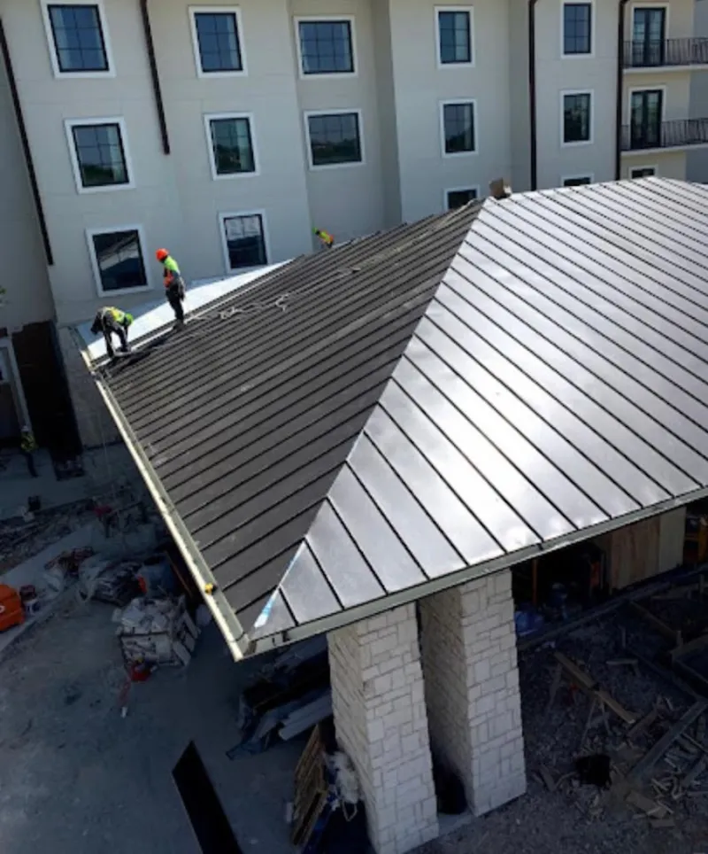 Crew installing standing seam metal roof panels on a commercial project in North Madison